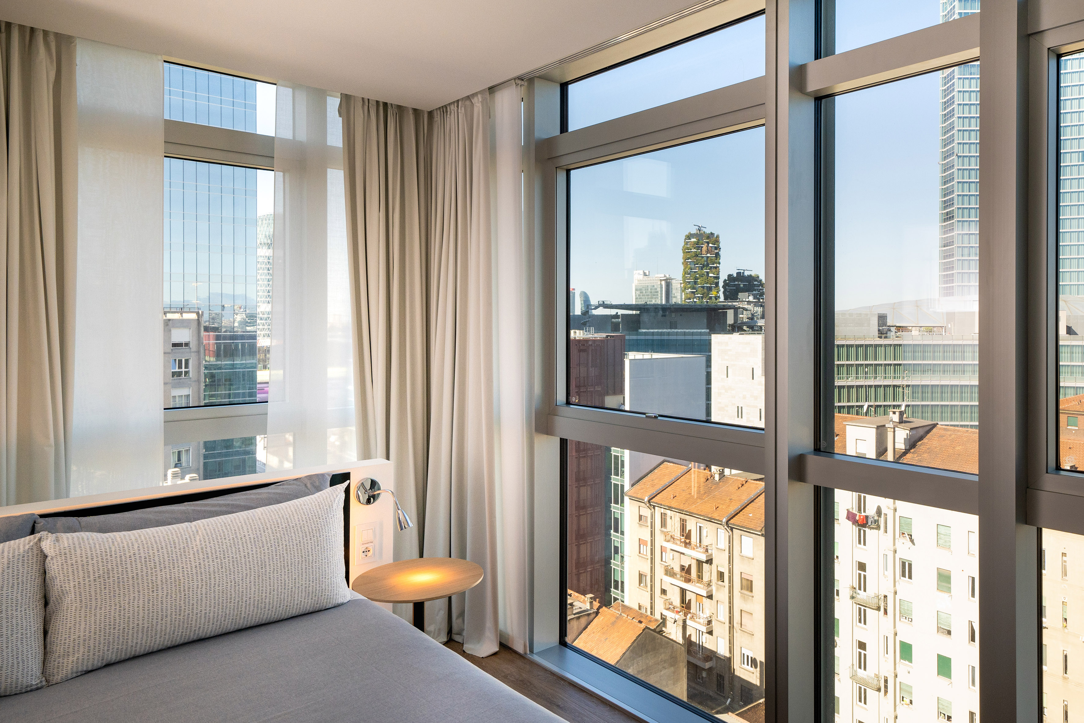 Modern hotel room, city view through large window, Milan skyline.