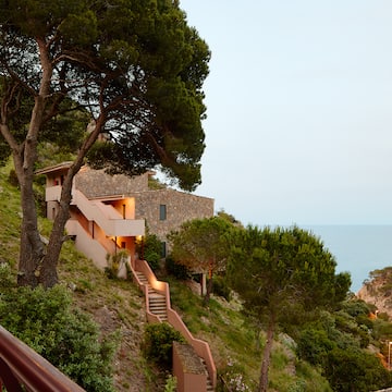 a building on a hill with trees and a railing