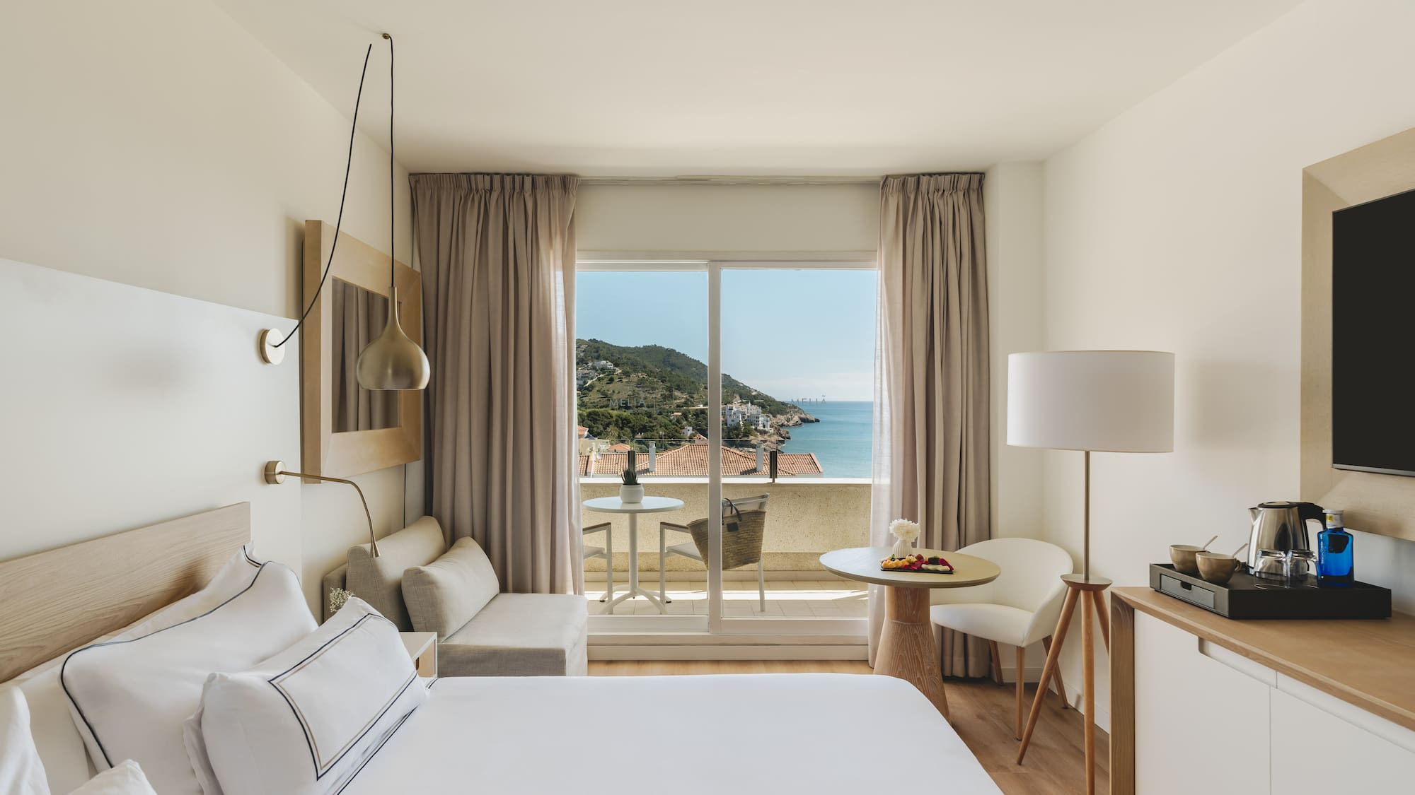 Modern hotel room with balcony, outdoor seating, and scenic coastal sea view.