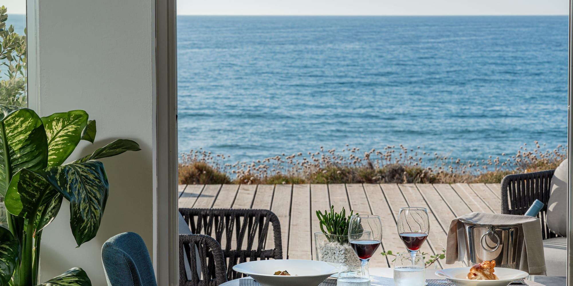 a table with food and glasses on it overlooking the ocean