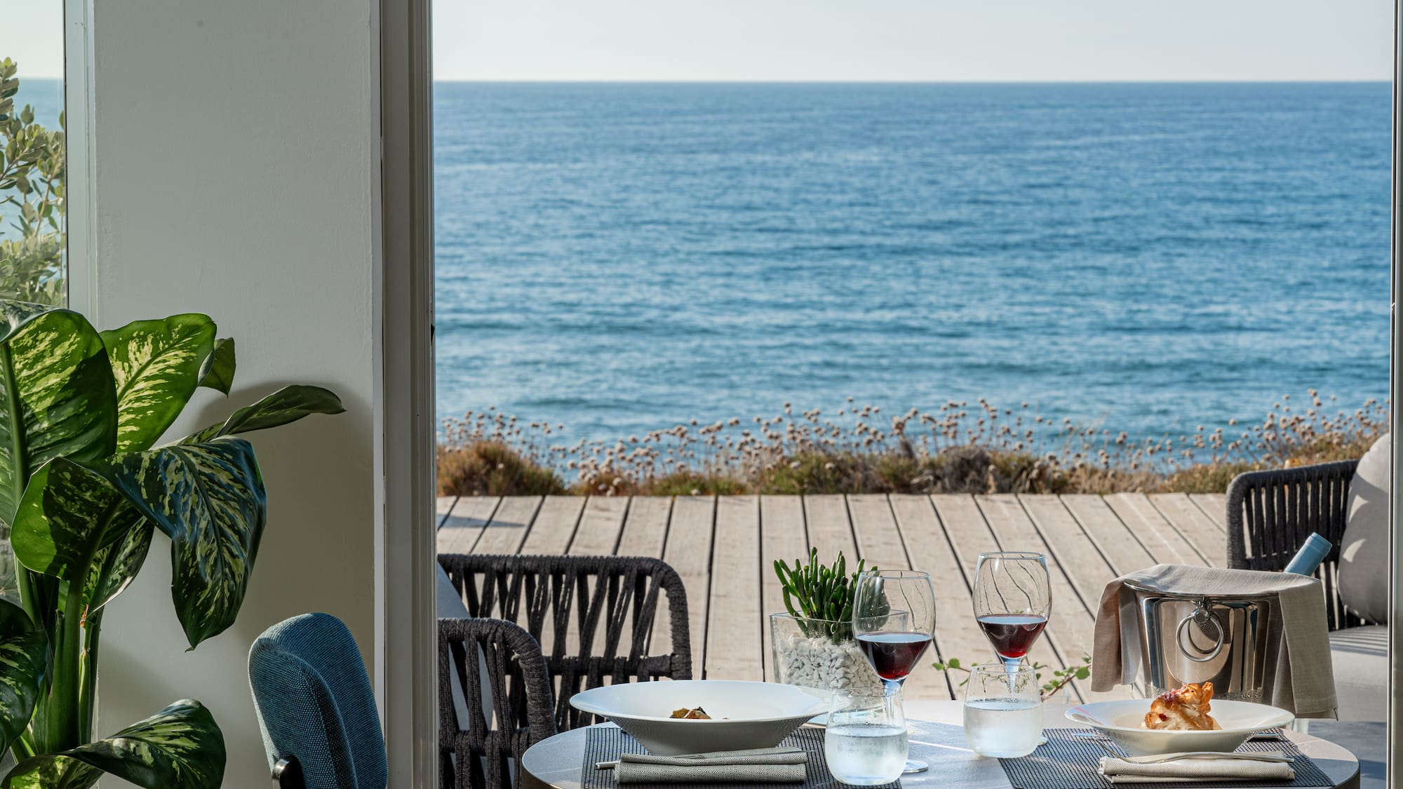a table with food and glasses on it overlooking the ocean
