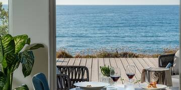 a table with food and glasses on it overlooking the ocean