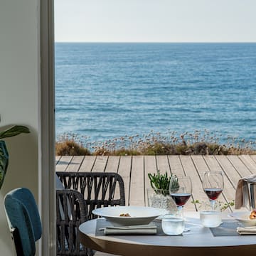 a table with food and glasses on it overlooking the ocean