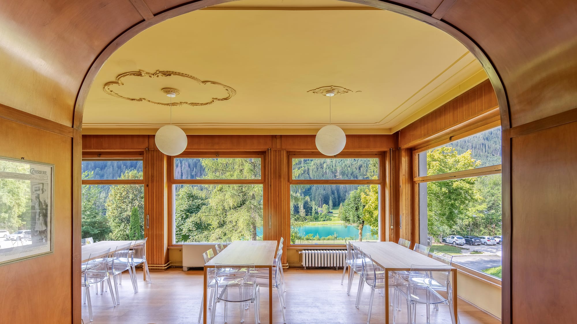 Wood interior room, panoramic lake & mountain views, modern clear chairs.