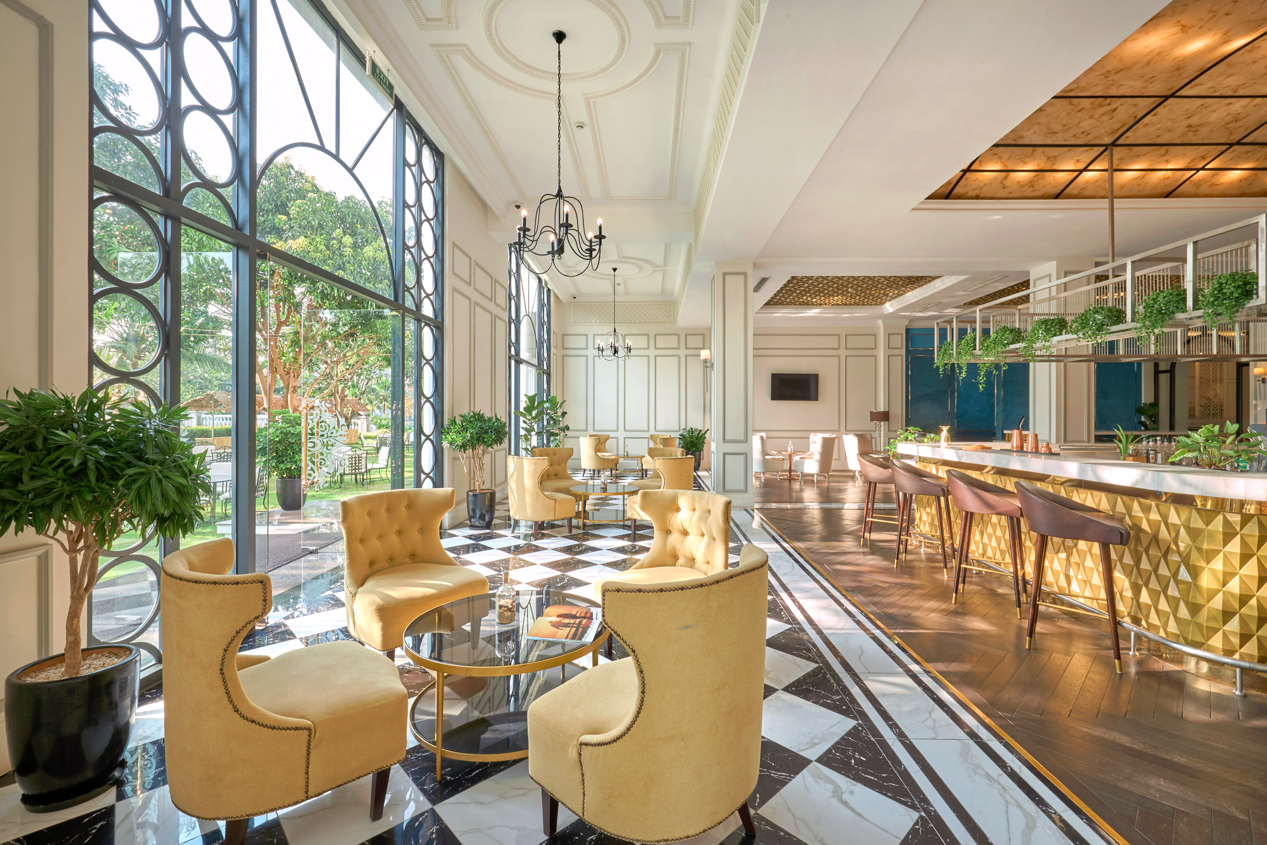 Hotel lobby lounge with checkered marble floor, gold velvet chairs, and bar.