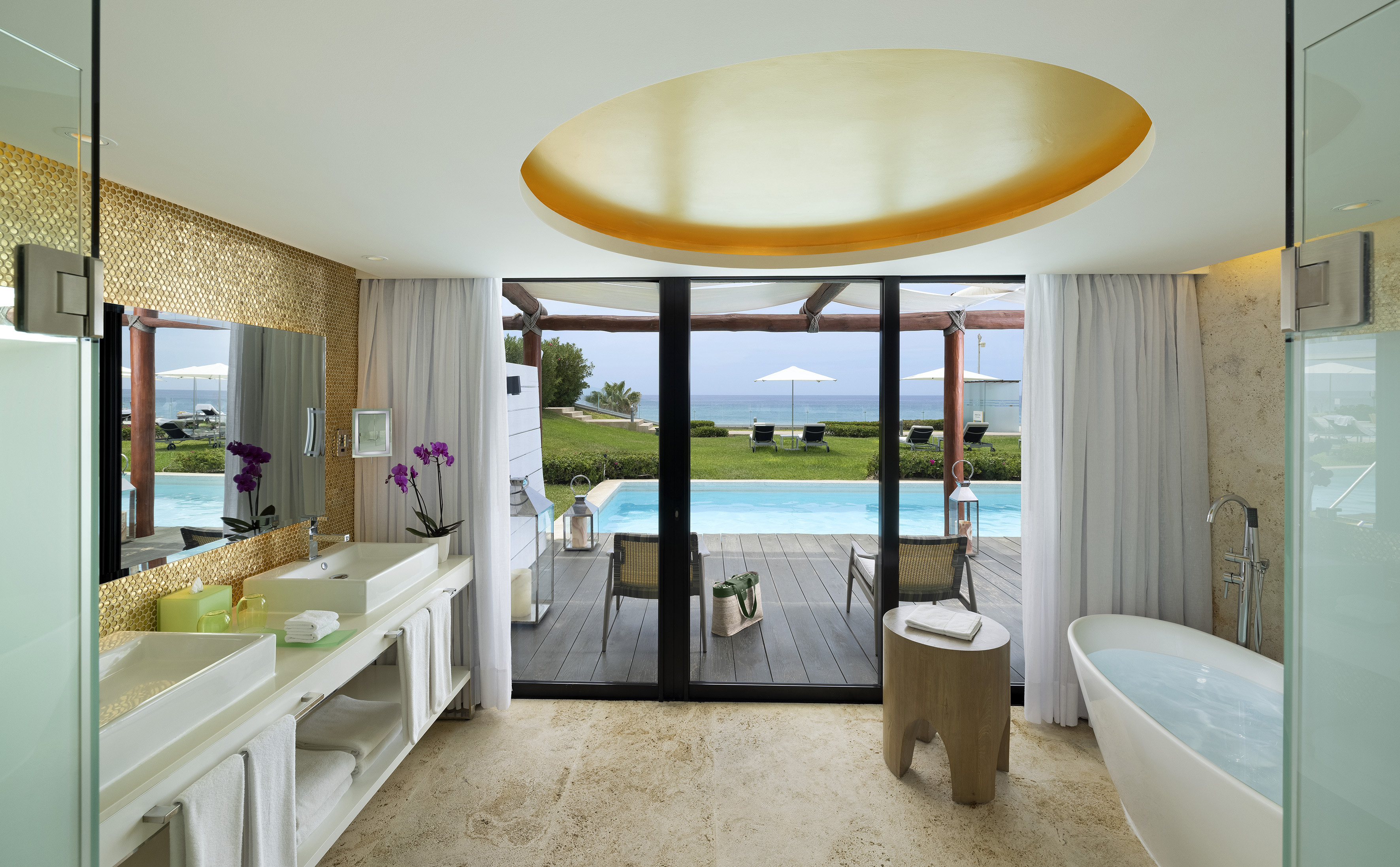 Luxury resort bathroom with private pool, ocean view, and freestanding tub.