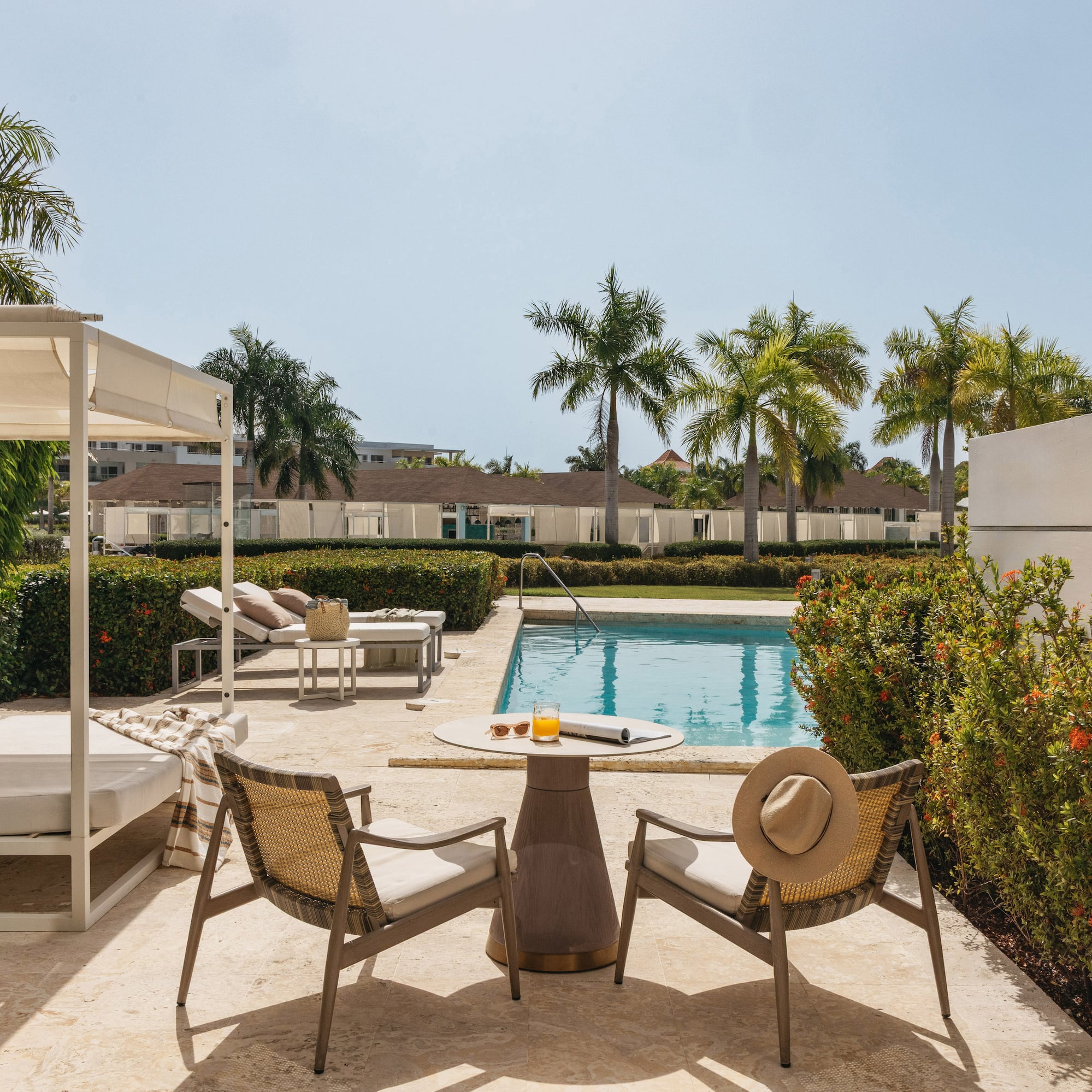 Resort patio with swimming pool, outdoor seating, and tropical palm trees.