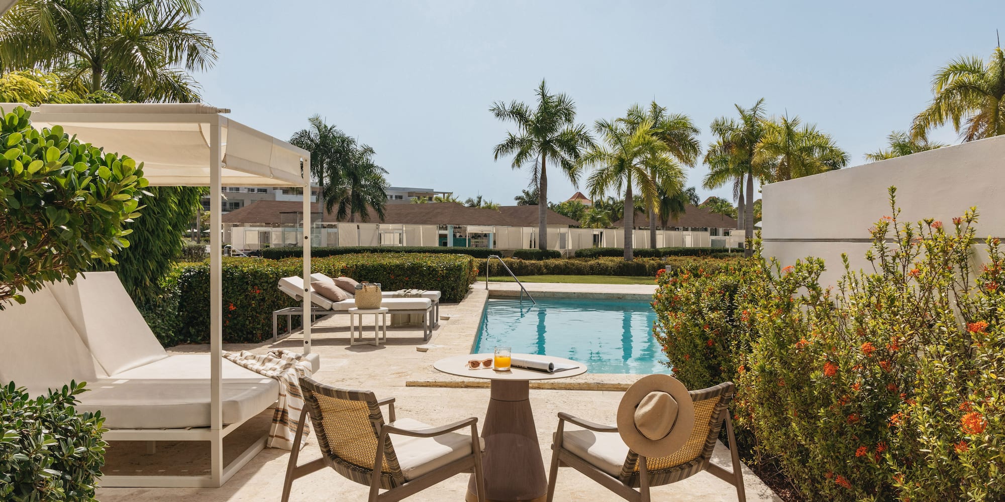 Resort patio with swimming pool, outdoor seating, and tropical palm trees.