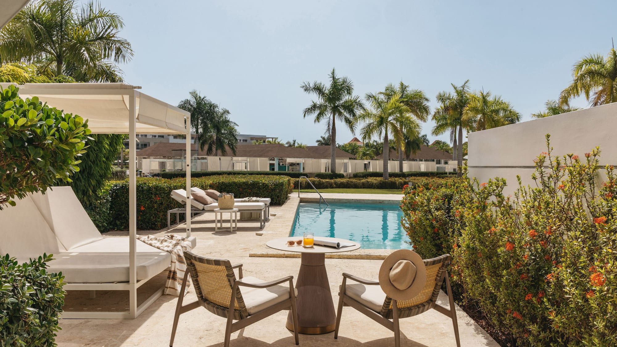 Tropical resort pool deck with daybeds, lounge chairs, and palm trees.
