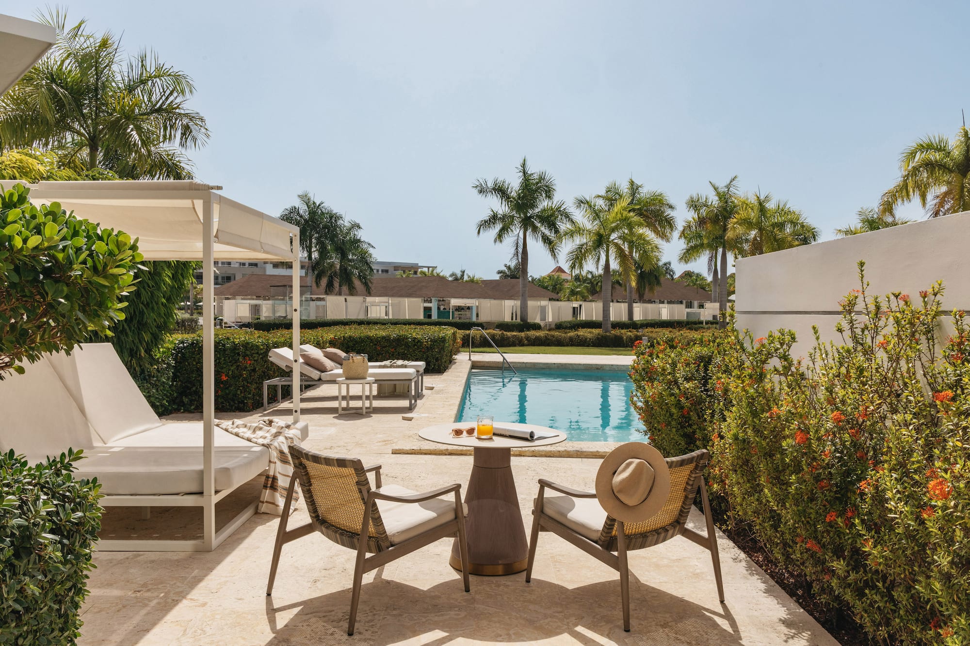Resort patio with swimming pool, outdoor seating, and tropical palm trees.