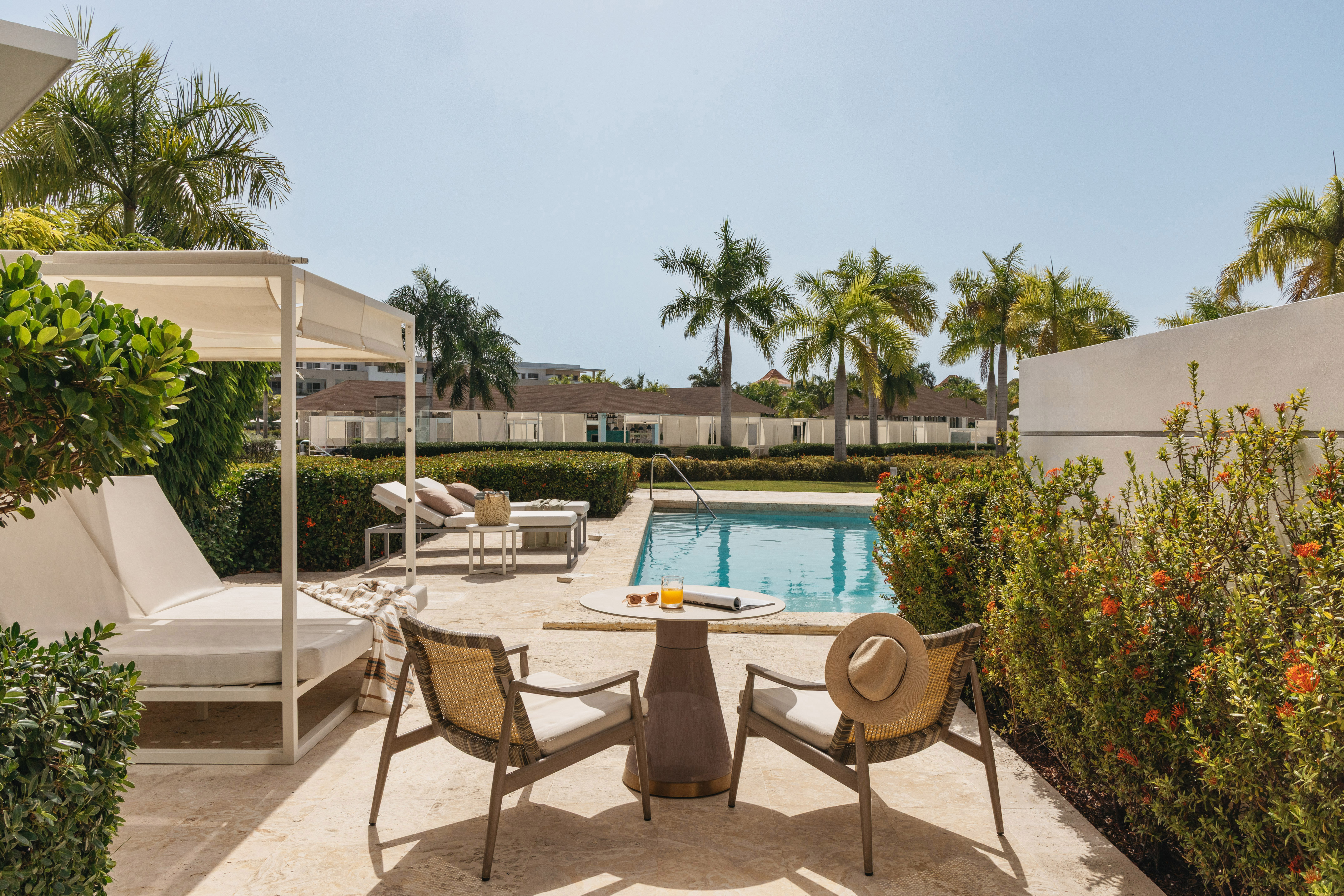 Resort patio with swimming pool, outdoor seating, and tropical palm trees.