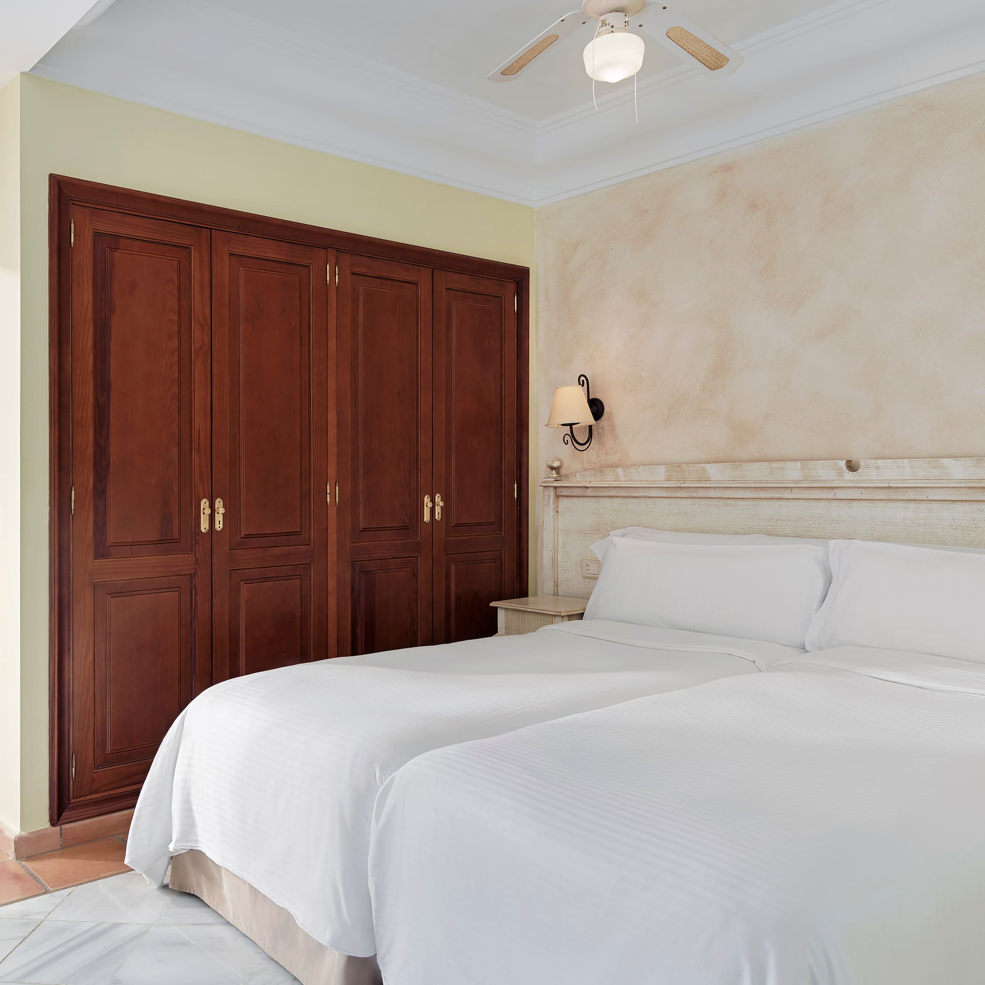 a room with two beds and a ceiling fan