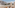 Modern hotel balcony with resort view, tiered building, and palm trees.