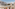 Modern hotel balcony with resort view, tiered building, and palm trees.