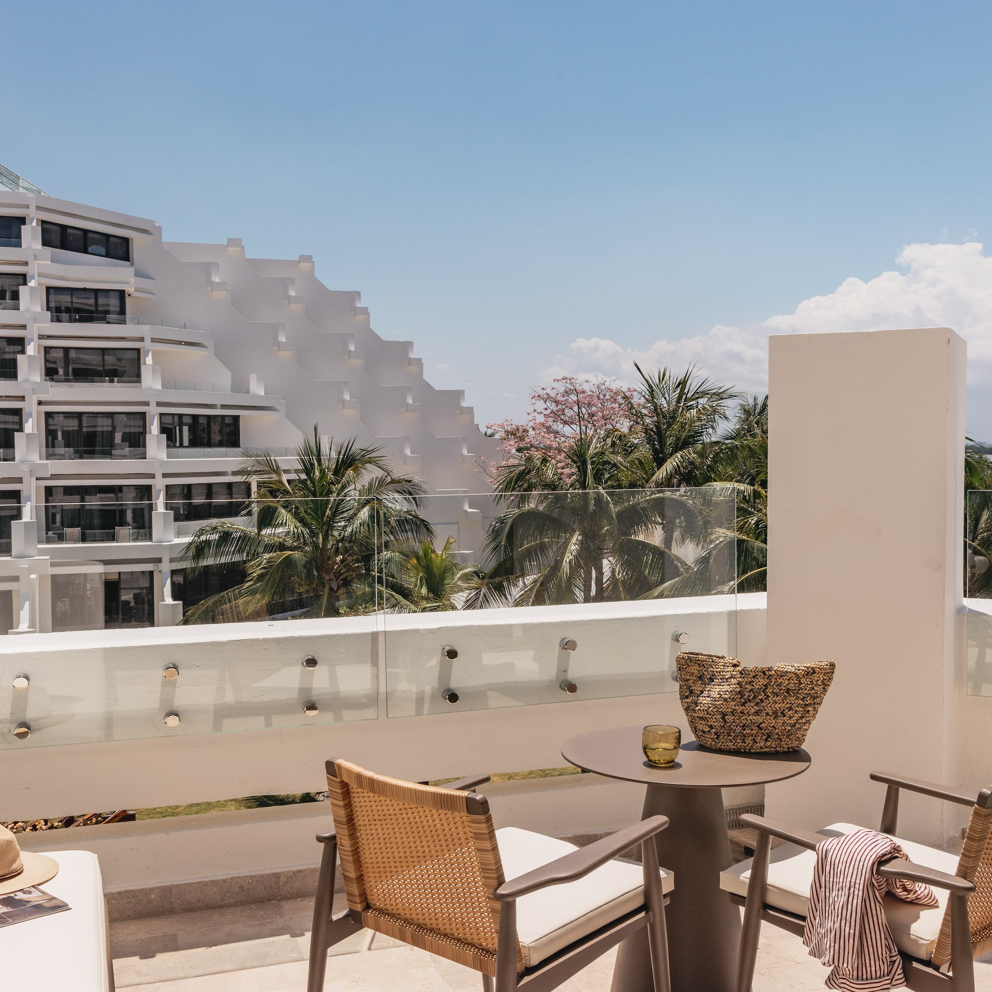Modern hotel balcony with resort view, tiered building, and palm trees.
