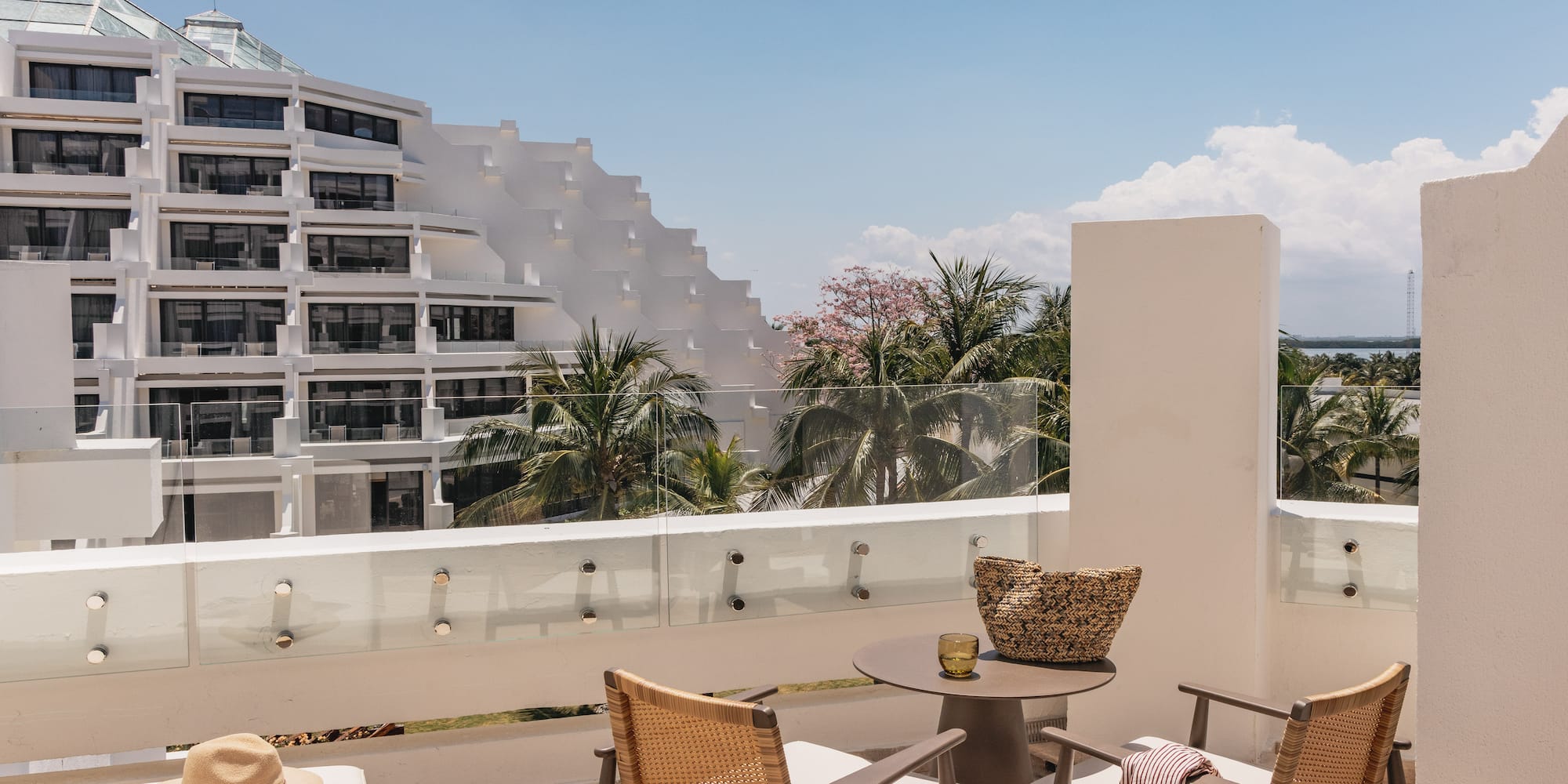 Modern hotel balcony with resort view, tiered building, and palm trees.