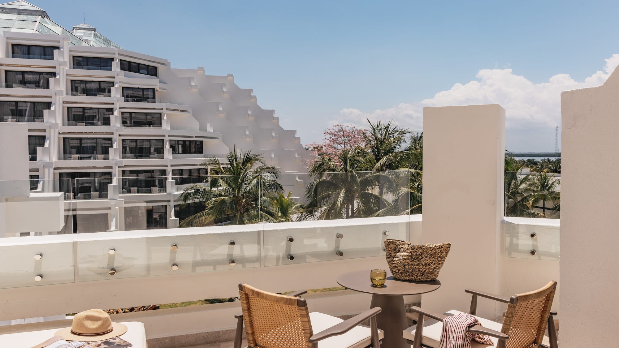 Modern hotel balcony with resort view, tiered building, and palm trees.