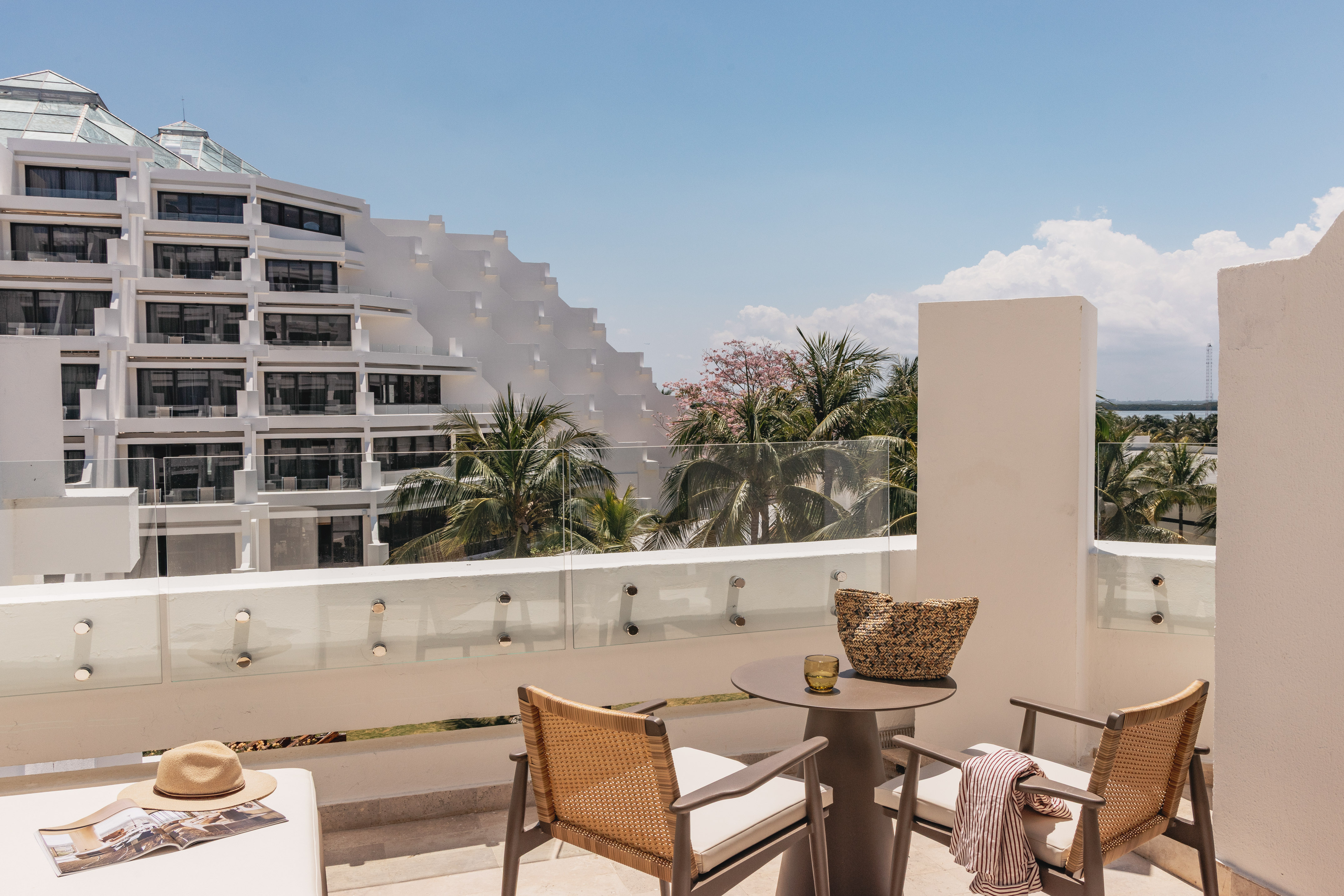 Modern hotel balcony with resort view, tiered building, and palm trees.