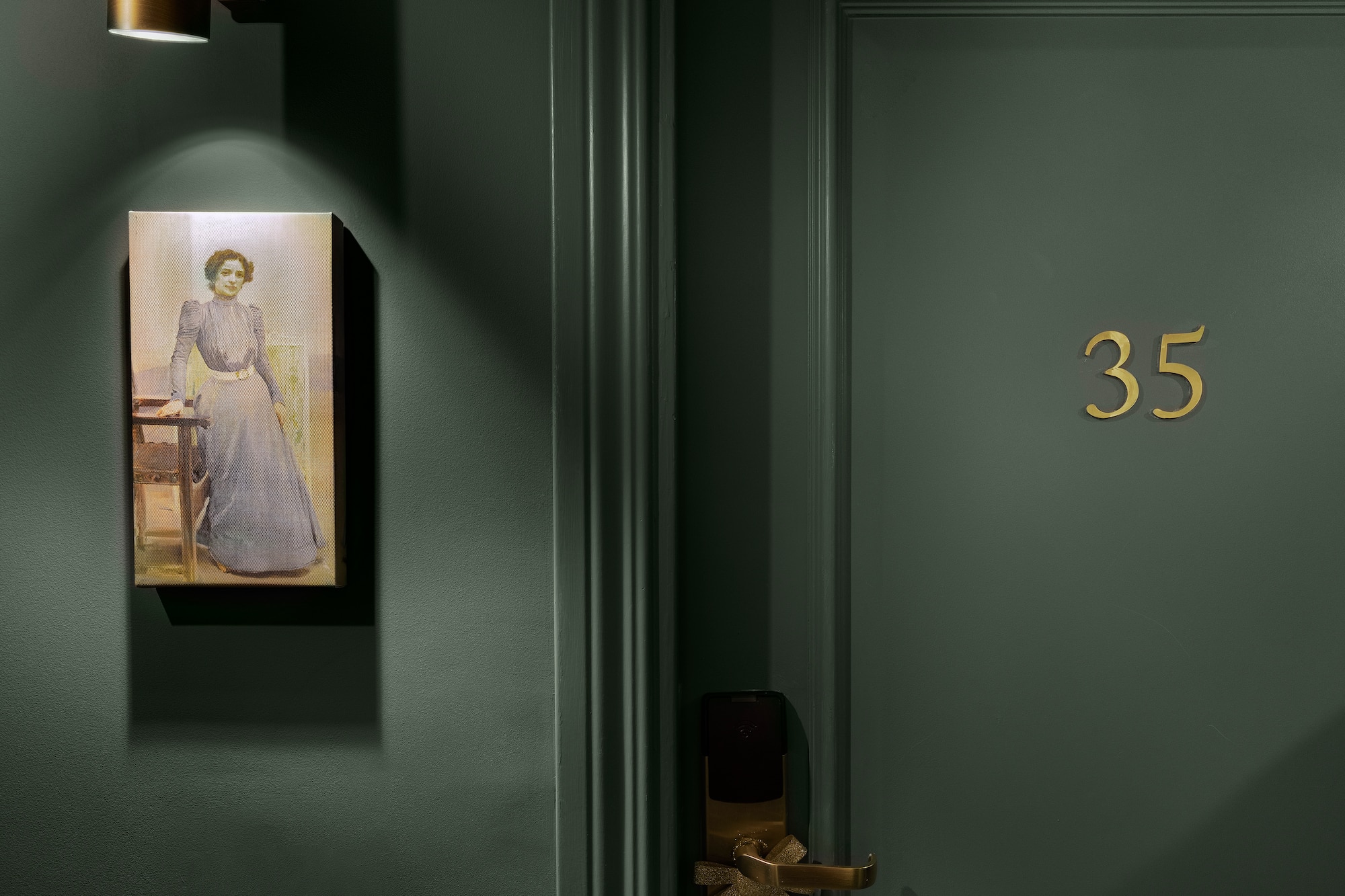 Dark green hotel door 35, gold accents, illuminated vintage portrait of a woman.