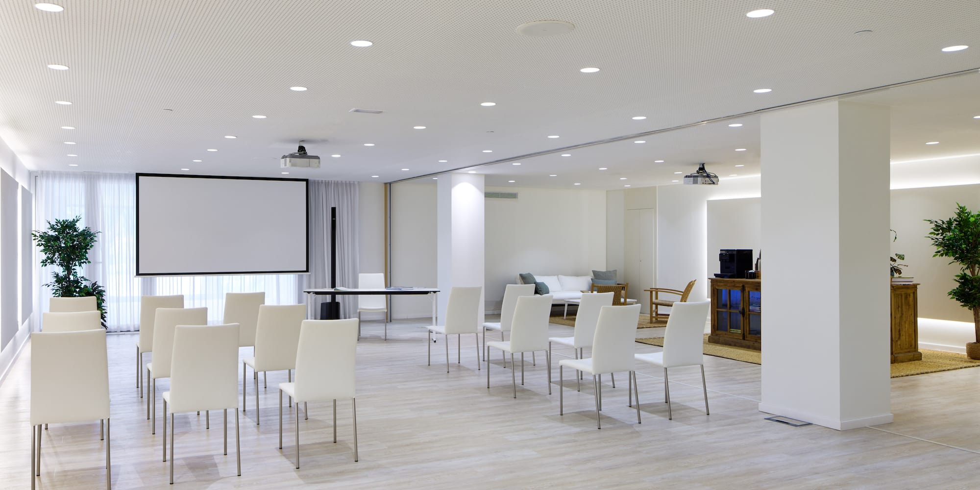 a room with white chairs and a projector screen