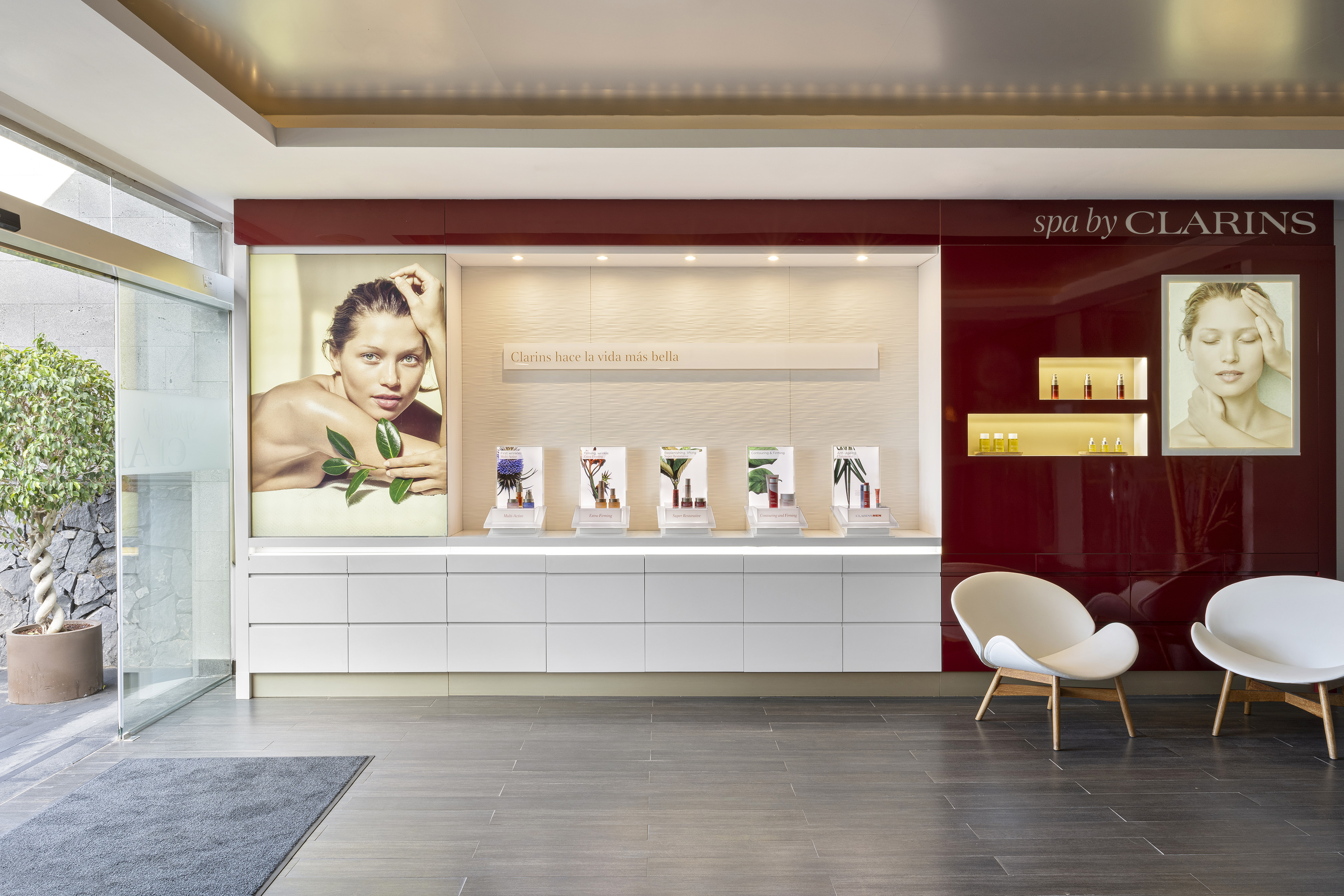 Clarins spa reception with skincare product display, model posters, and seating.