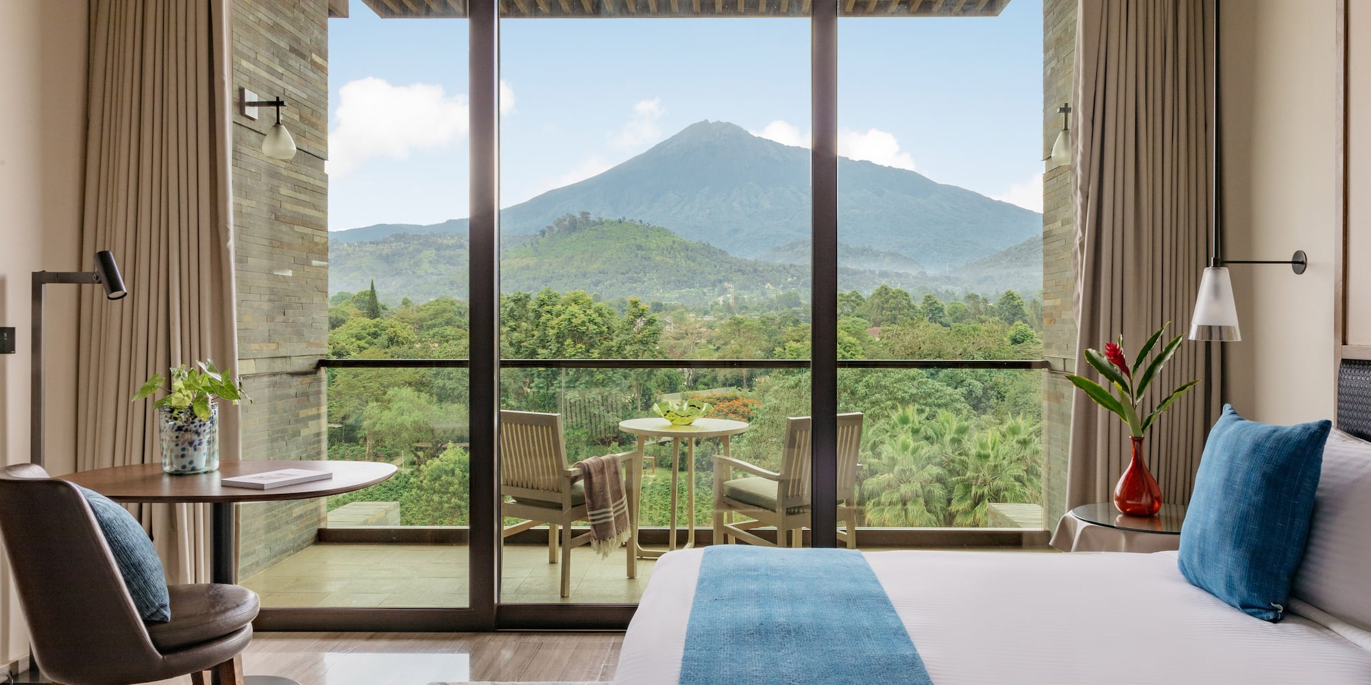 Hotel room with balcony overlooking a majestic mountain and lush forest.