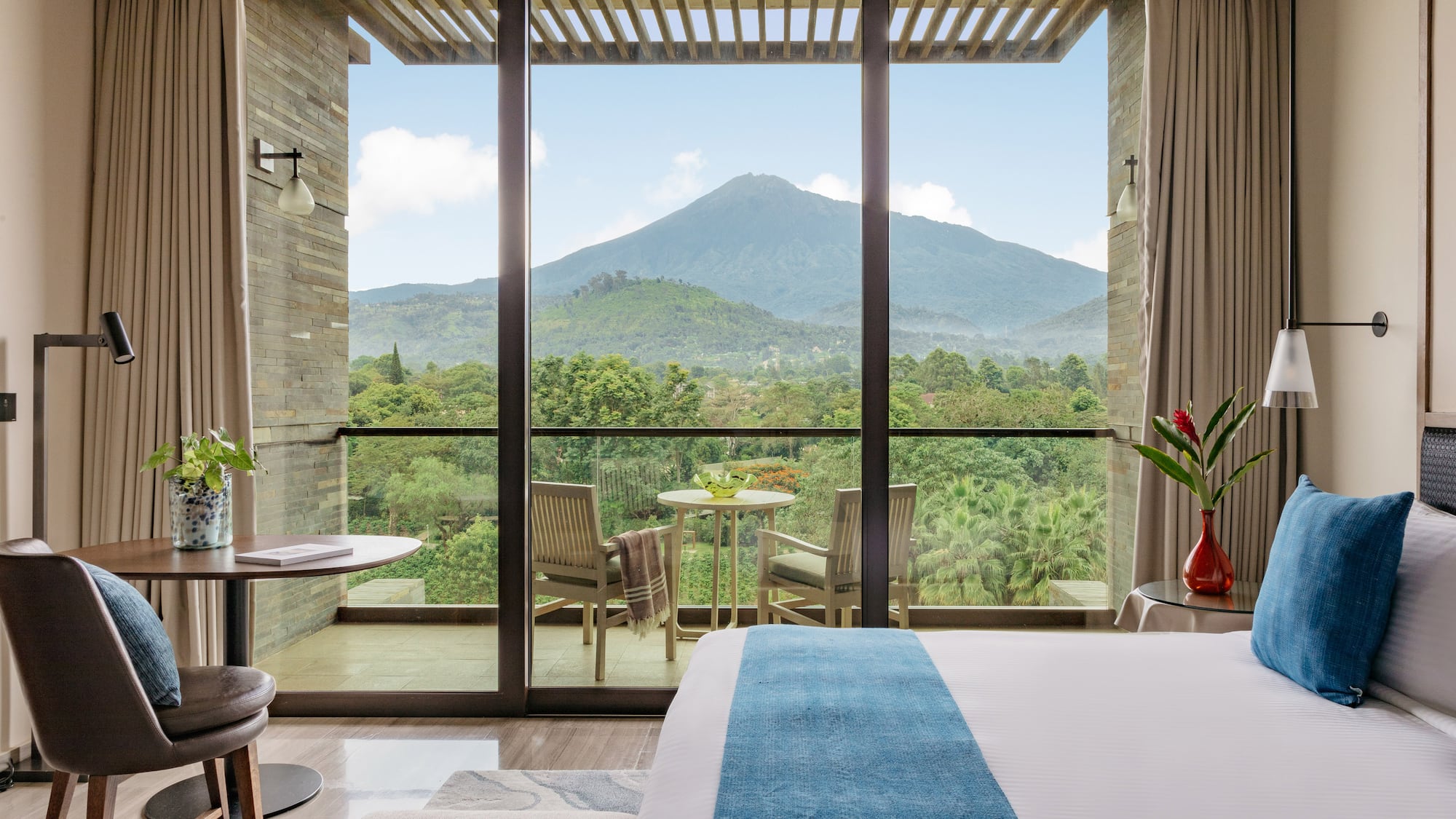 Hotel room with balcony overlooking a majestic mountain and lush forest.