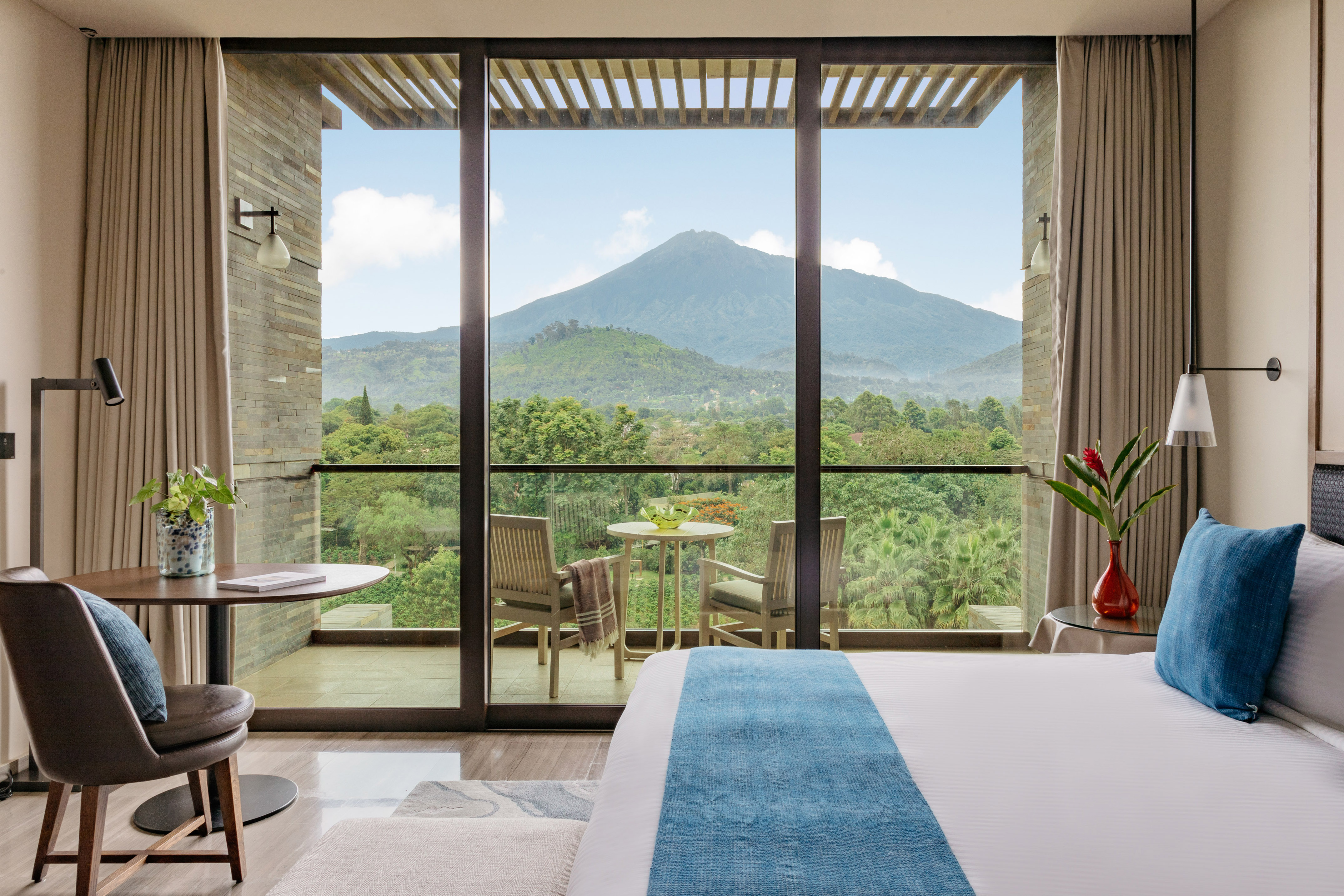 Hotel room with balcony overlooking a majestic mountain and lush forest.