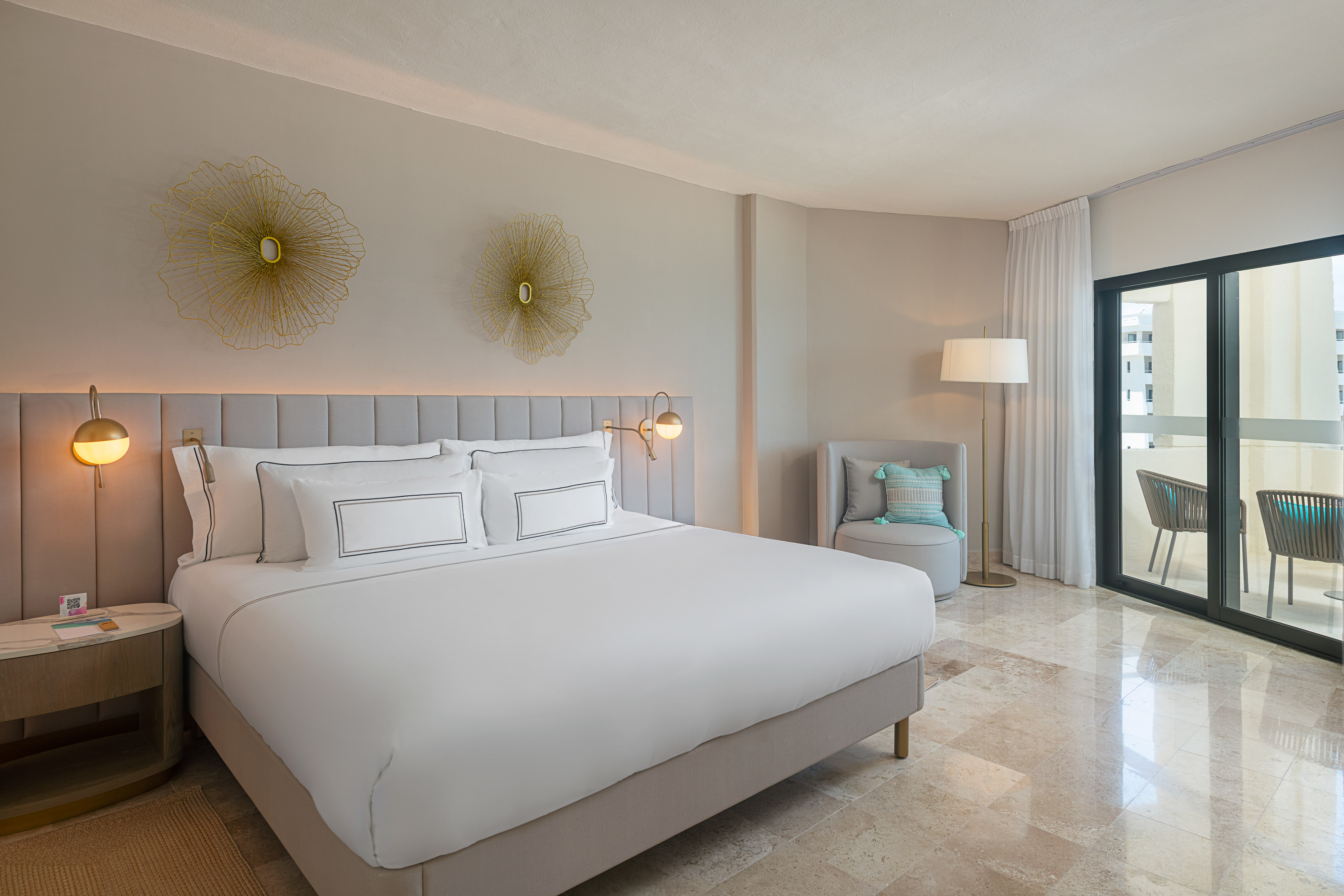 Modern hotel bedroom with king bed, elegant decor, marble floor, and balcony.
