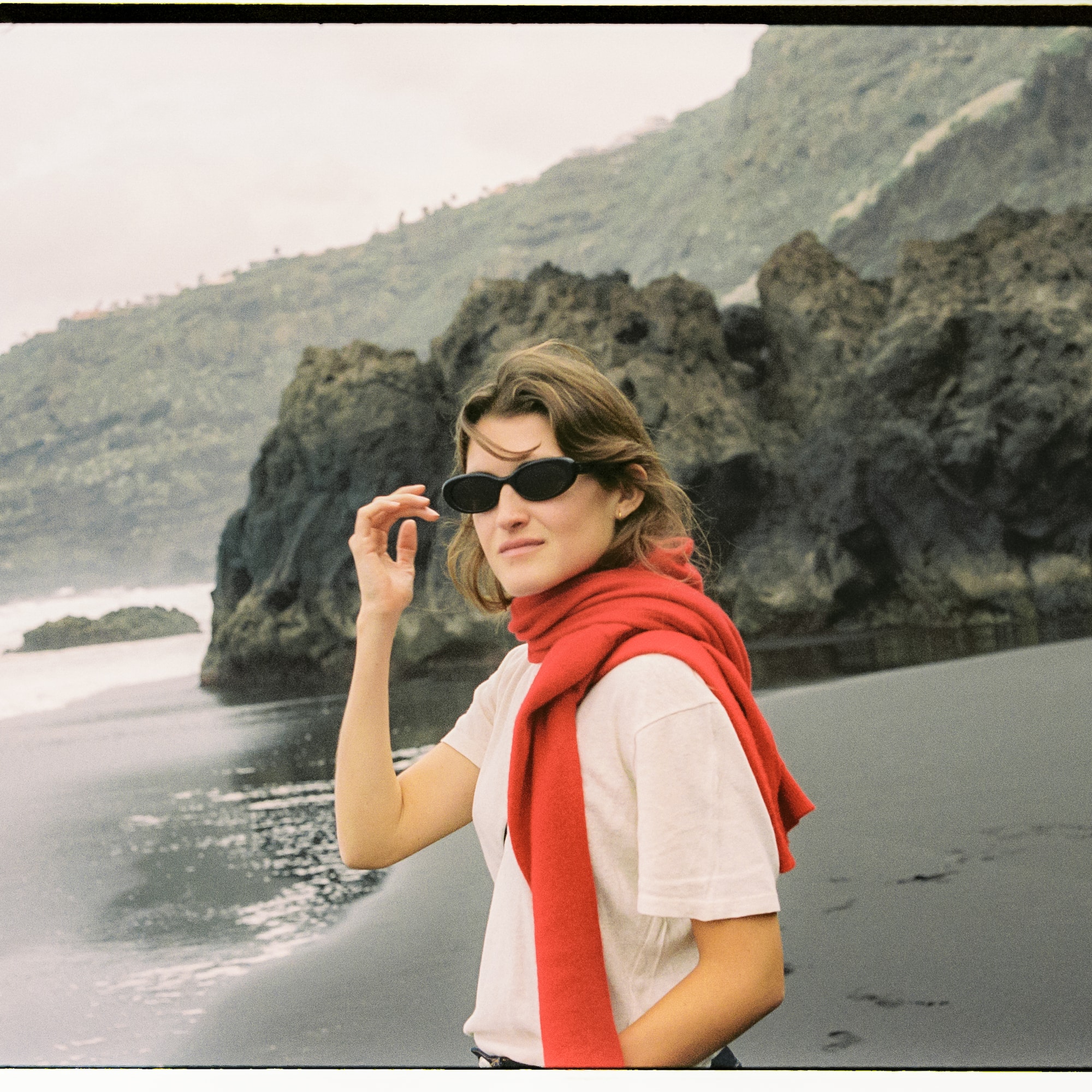a woman wearing sunglasses and a red scarf on a beach
