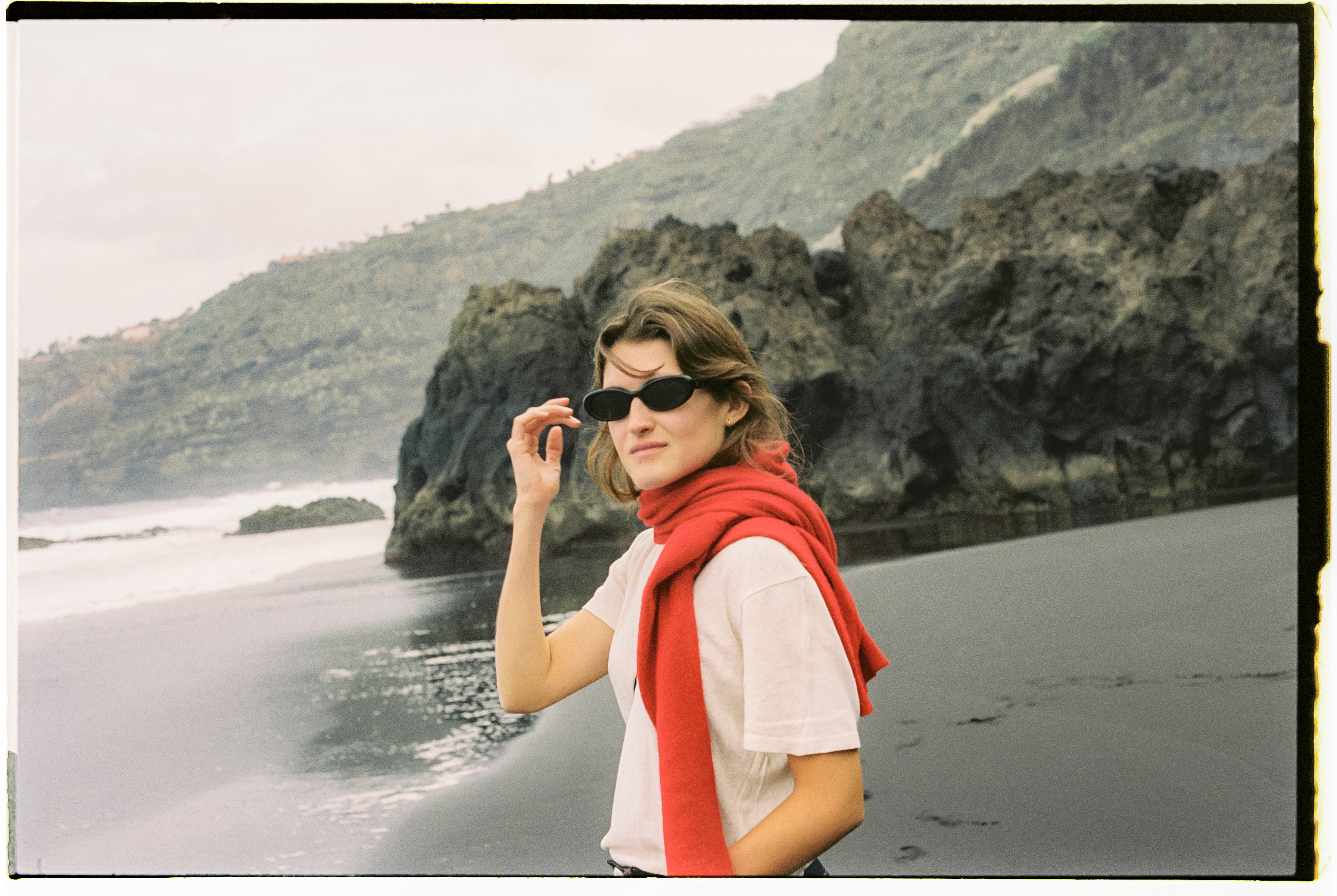 a woman wearing sunglasses and a red scarf on a beach