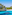 Crystal clear turquoise bay, white sand beach, and rocky pine cliffs.