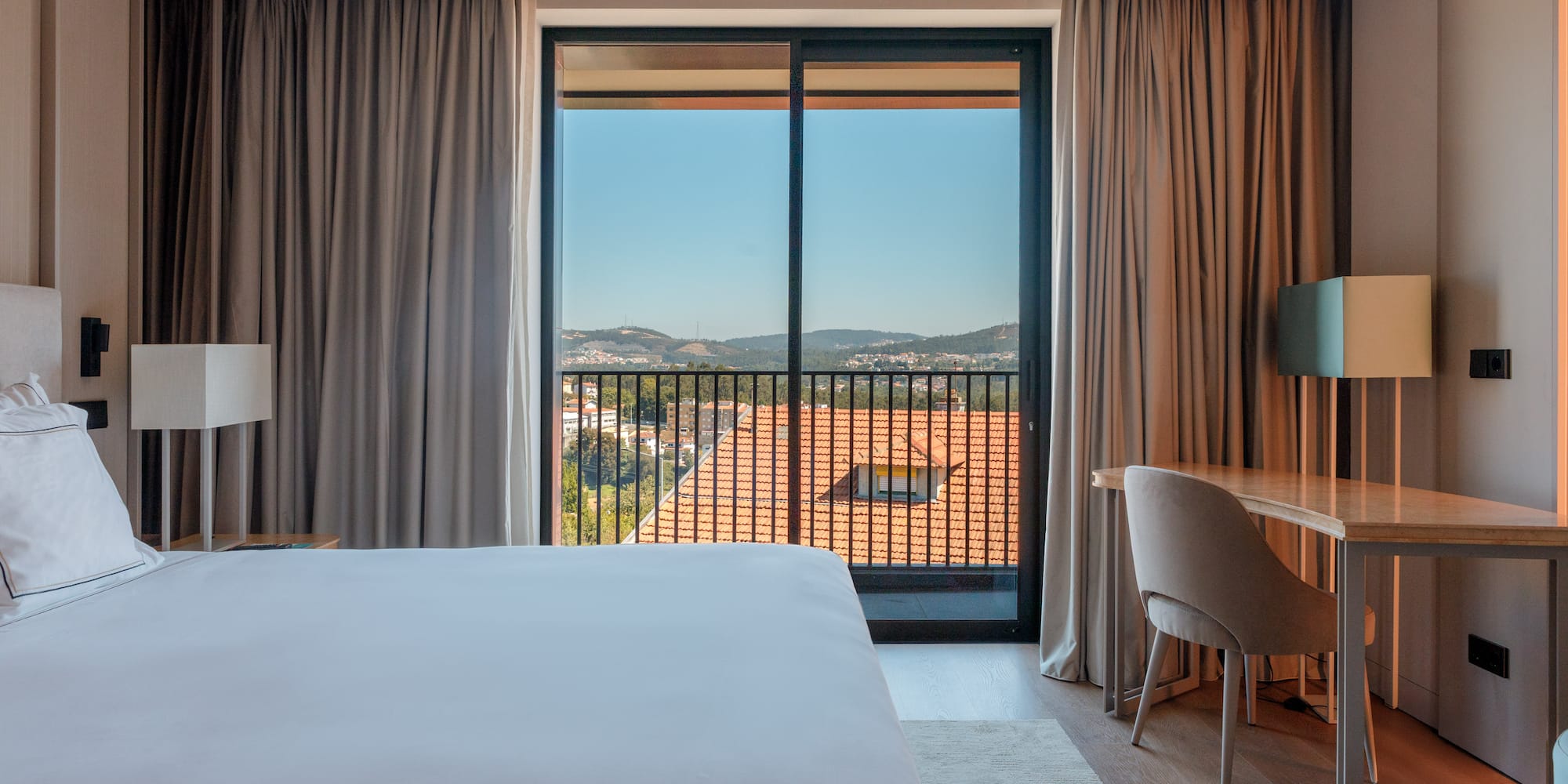 a room with a bed and a desk and a balcony