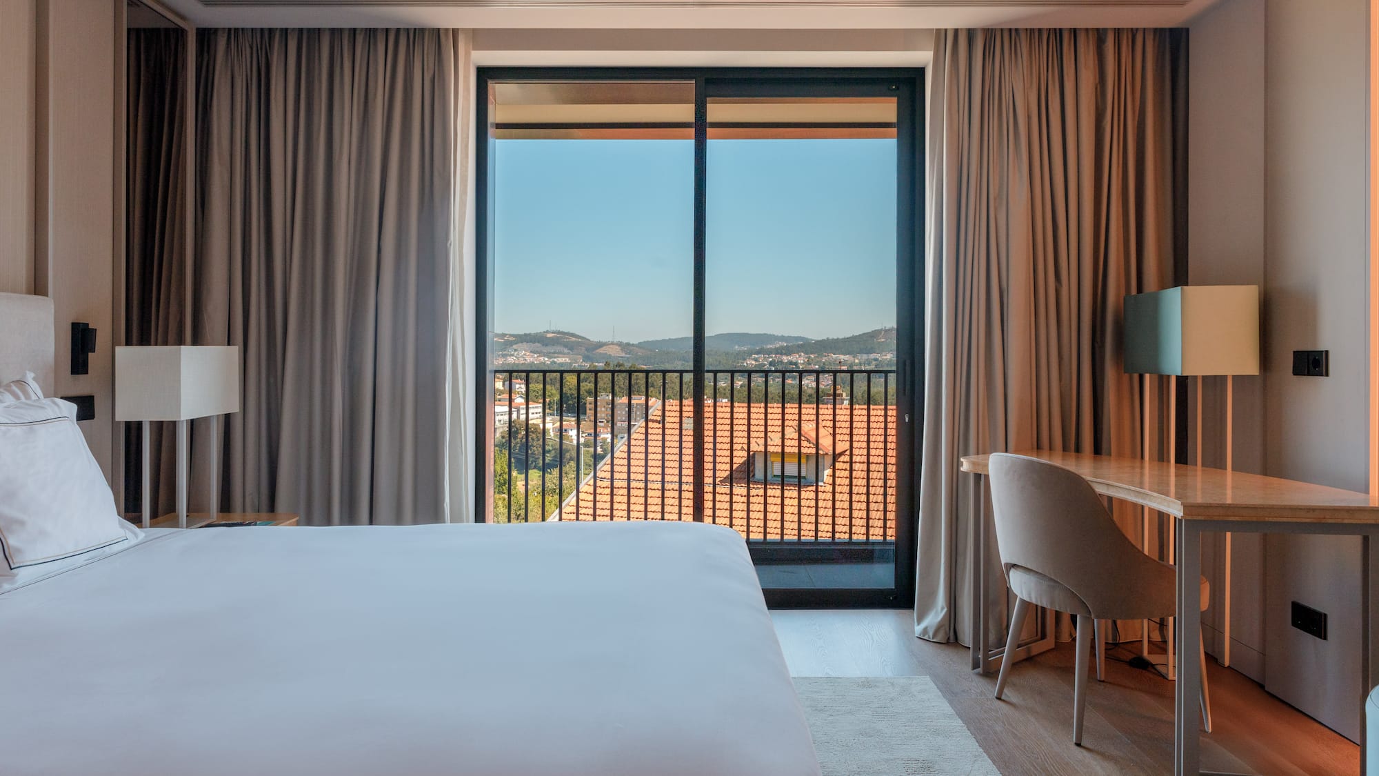 a room with a bed and a desk and a balcony