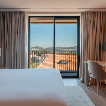 a room with a bed and a desk and a balcony