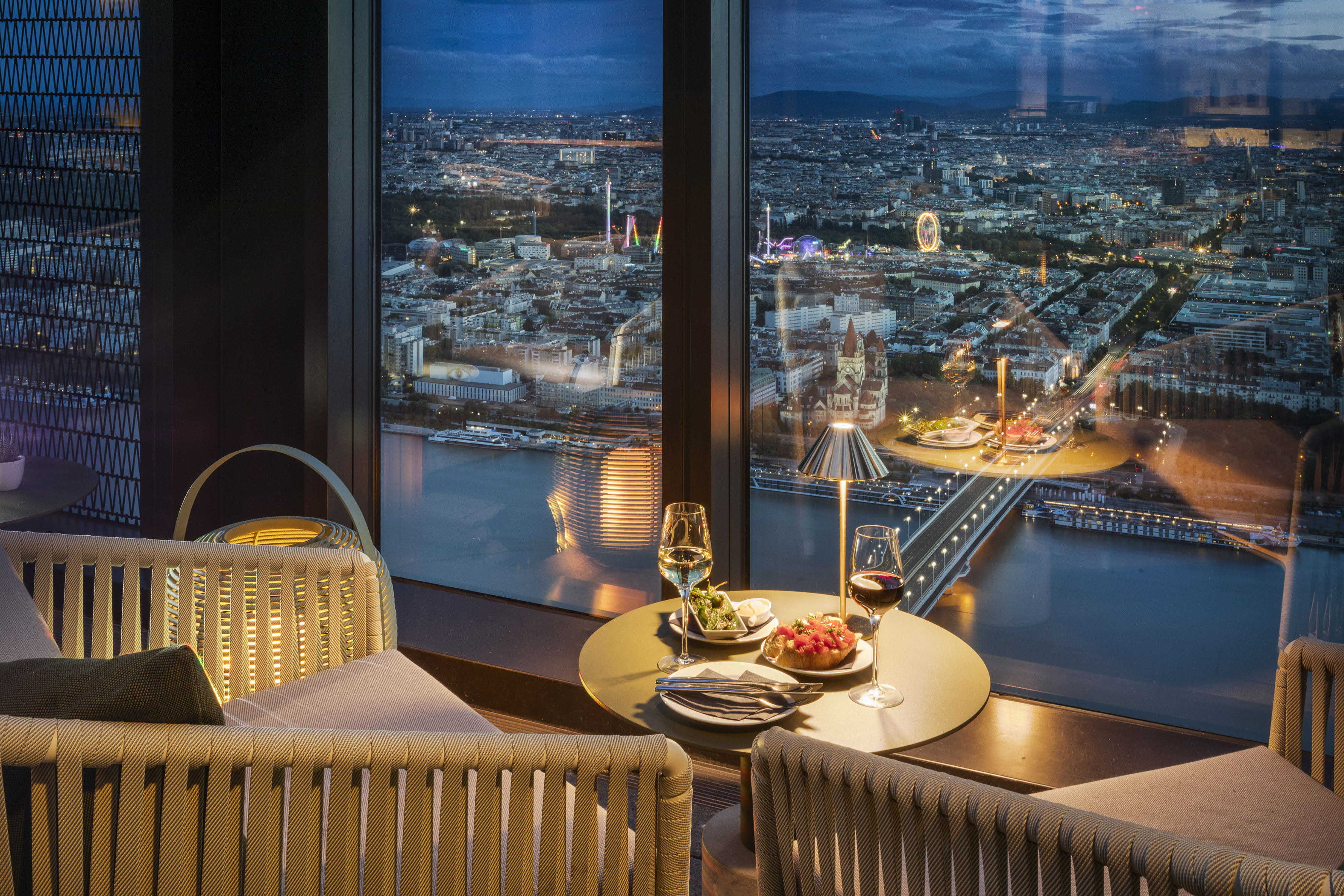 Elegant rooftop bar with panoramic Vienna city night view, drinks, appetizers.