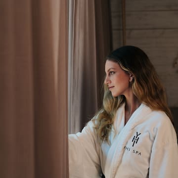 a woman in a bathrobe looking out a window