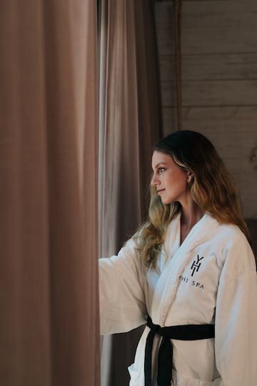 a woman in a bathrobe looking out a window