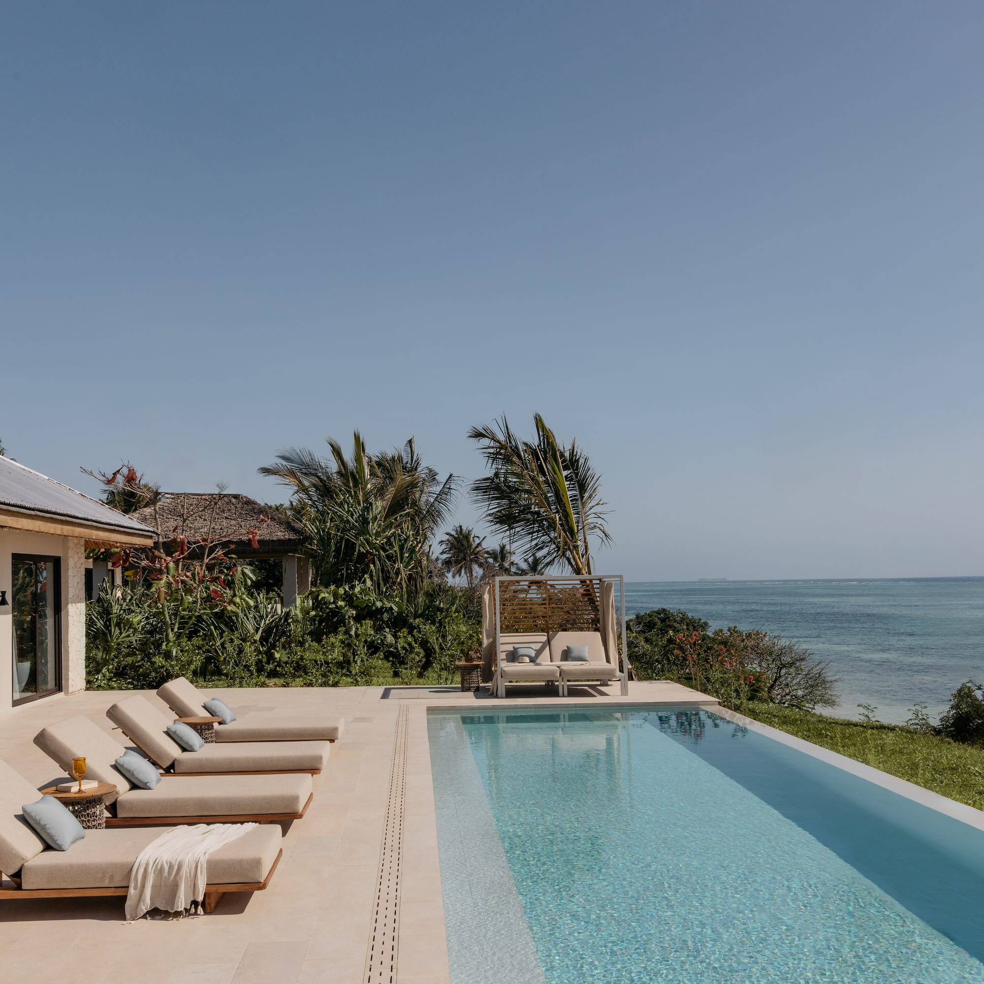 a pool with lounge chairs and a beach view