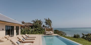 a pool with lounge chairs and a beach view