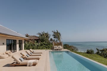 a pool with lounge chairs and a beach view
