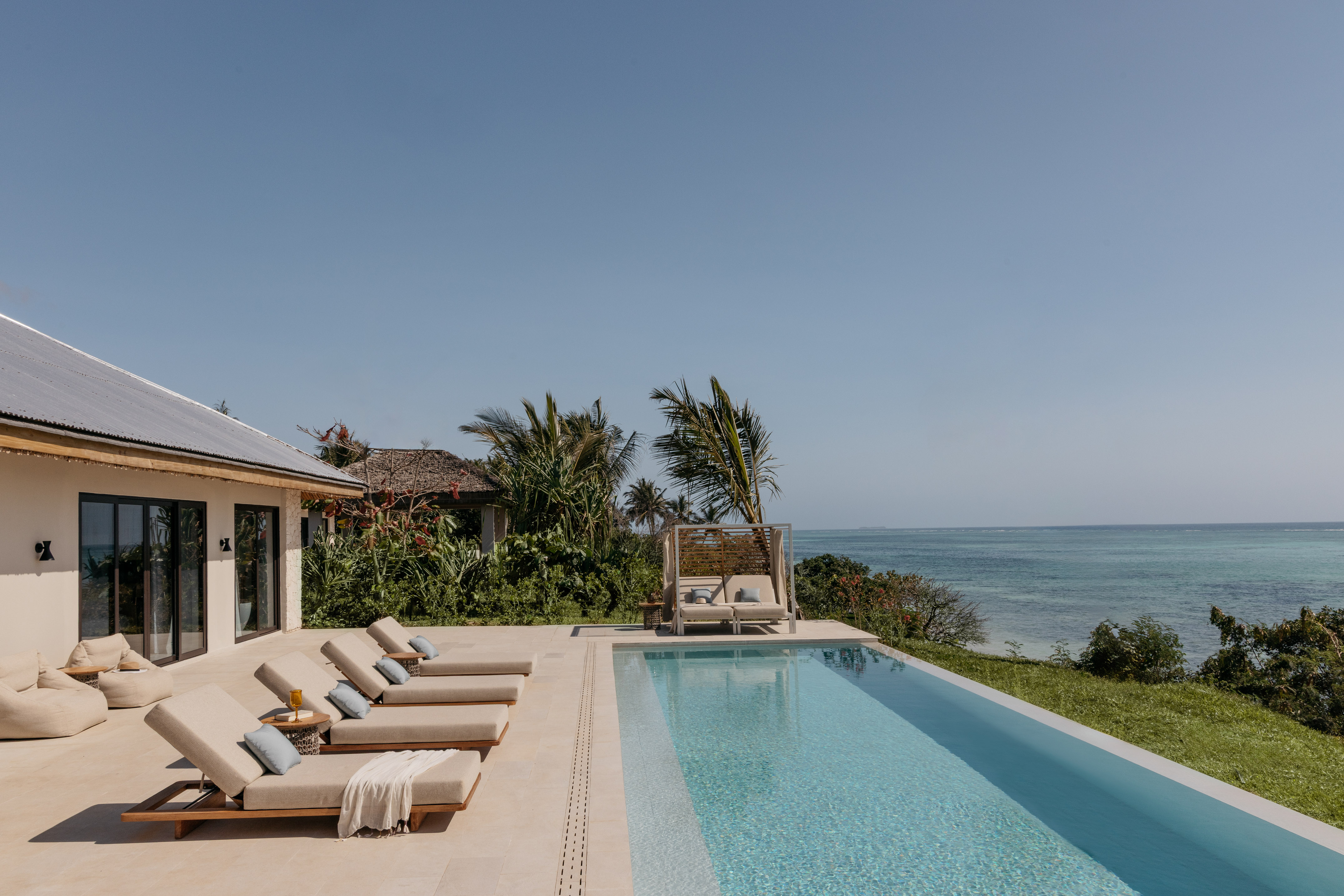 a pool with lounge chairs and a beach view