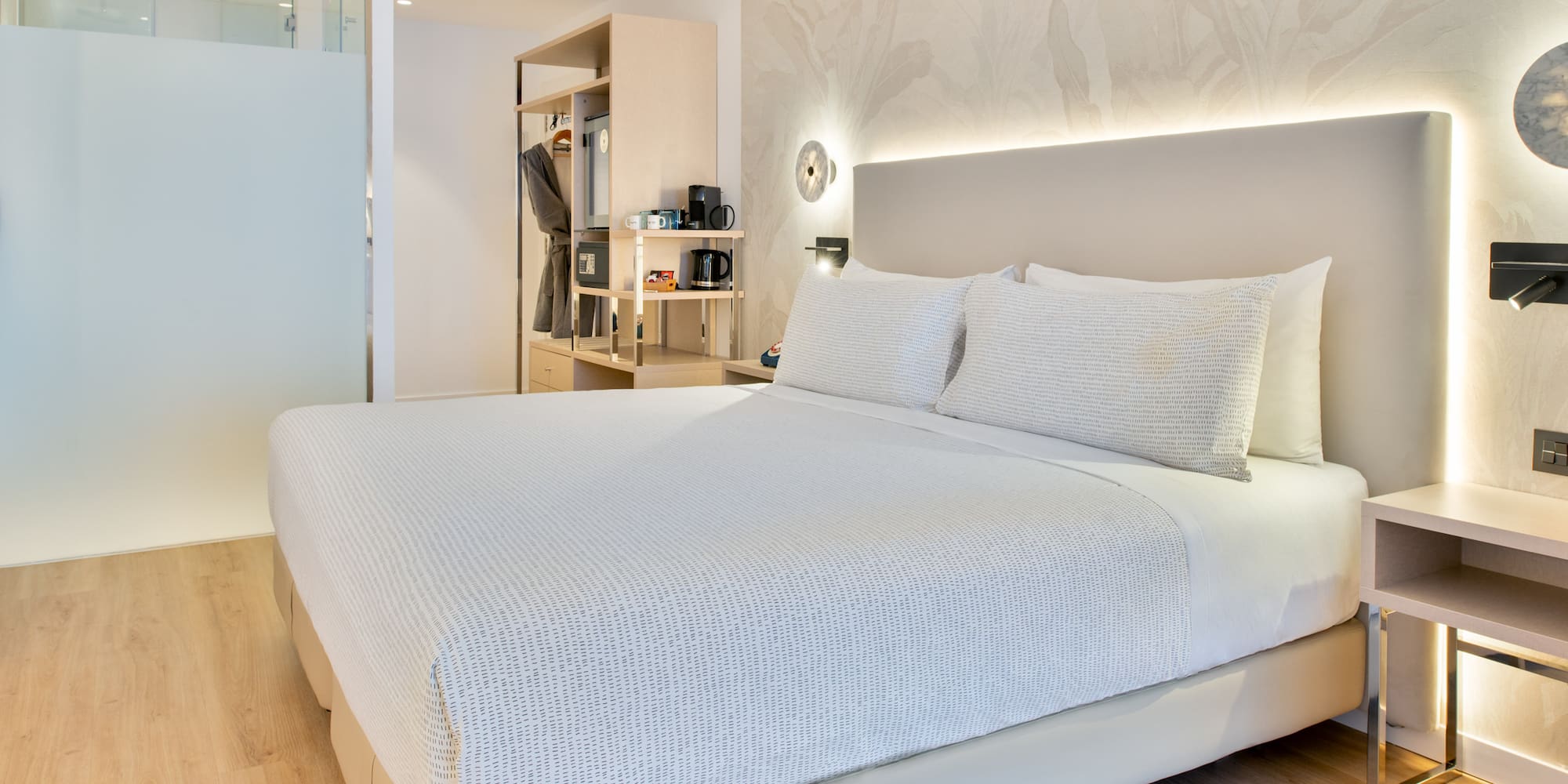 a bed with white sheets and pillows in a room
