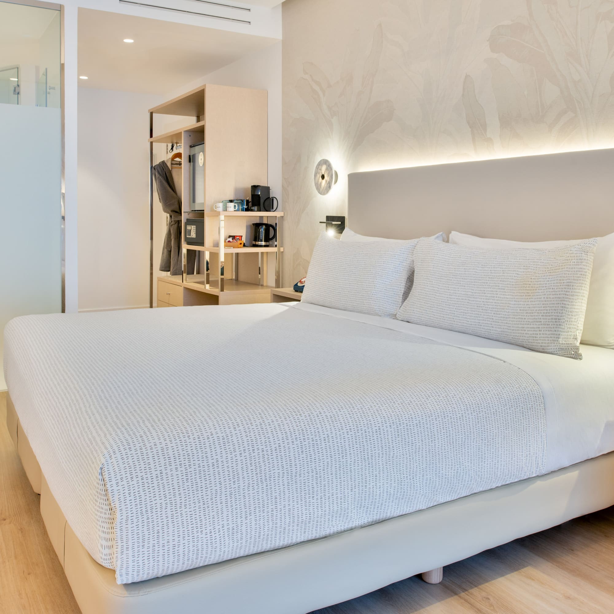 a bed with white sheets and pillows in a room
