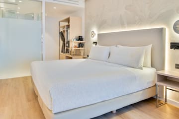 a bed with white sheets and pillows in a room