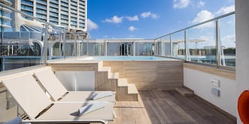 a deck with chairs and a pool on a rooftop