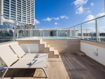 a deck with chairs and a pool on a rooftop