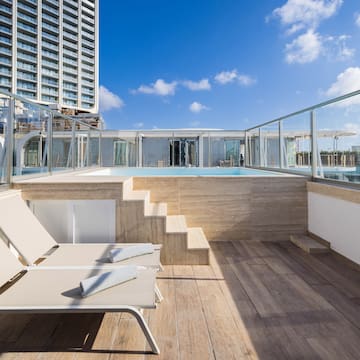 a deck with chairs and a pool on a rooftop