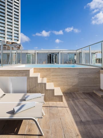 a deck with chairs and a pool on a rooftop