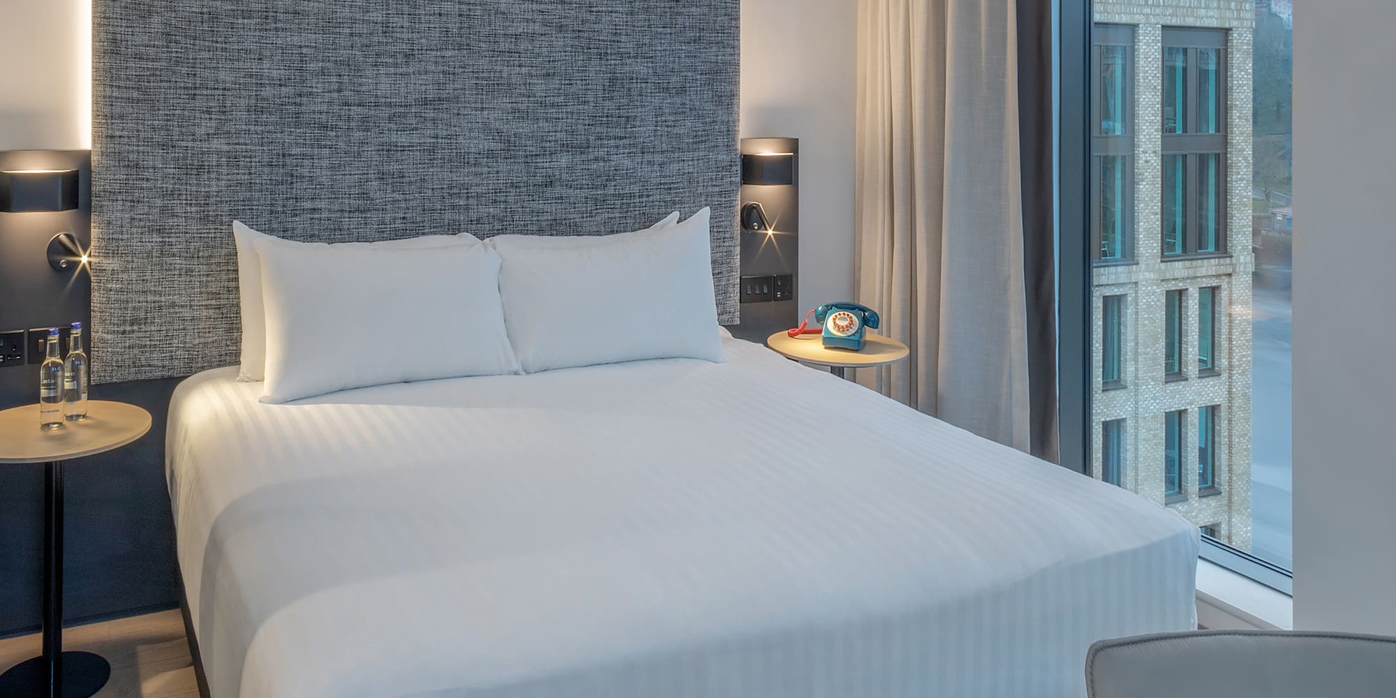 a bed with a headboard and a table with a telephone on it